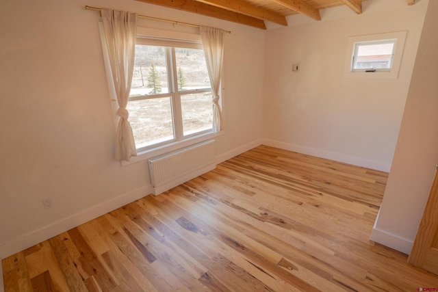 spare room featuring baseboards, radiator heating unit, beam ceiling, and plenty of natural light