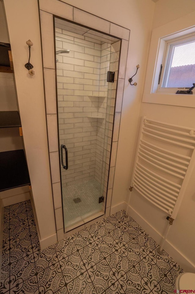 bathroom with radiator, baseboards, tile patterned floors, and a stall shower