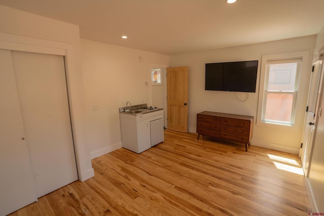 unfurnished bedroom featuring light wood finished floors, baseboards, recessed lighting, and a sink
