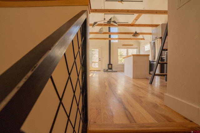 hallway with light wood-style floors and lofted ceiling with beams