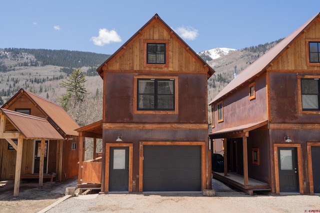 view of front of property with gravel driveway, metal roof, a mountain view, and a garage
