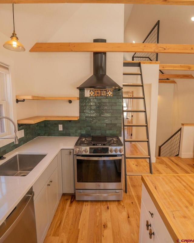 kitchen featuring a sink, decorative backsplash, stainless steel appliances, light wood finished floors, and range hood