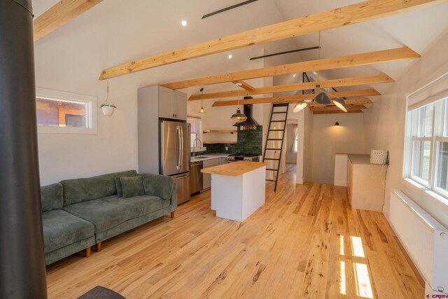 living room featuring radiator heating unit, vaulted ceiling with beams, light wood finished floors, and recessed lighting