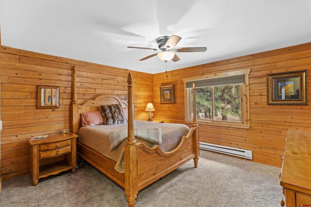 carpeted bedroom featuring a baseboard heating unit, ceiling fan, and wooden walls