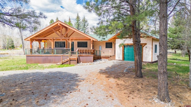 view of front of house with driveway, a porch, and stucco siding