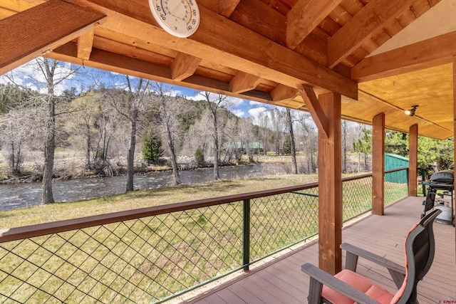 deck featuring a lawn, a grill, and a water and mountain view