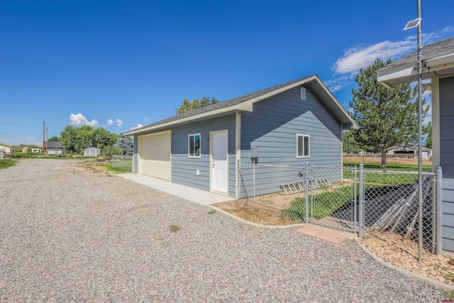 view of property exterior with fence, a gate, and a detached garage