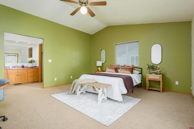 bedroom with light carpet, vaulted ceiling, ensuite bath, and a sink