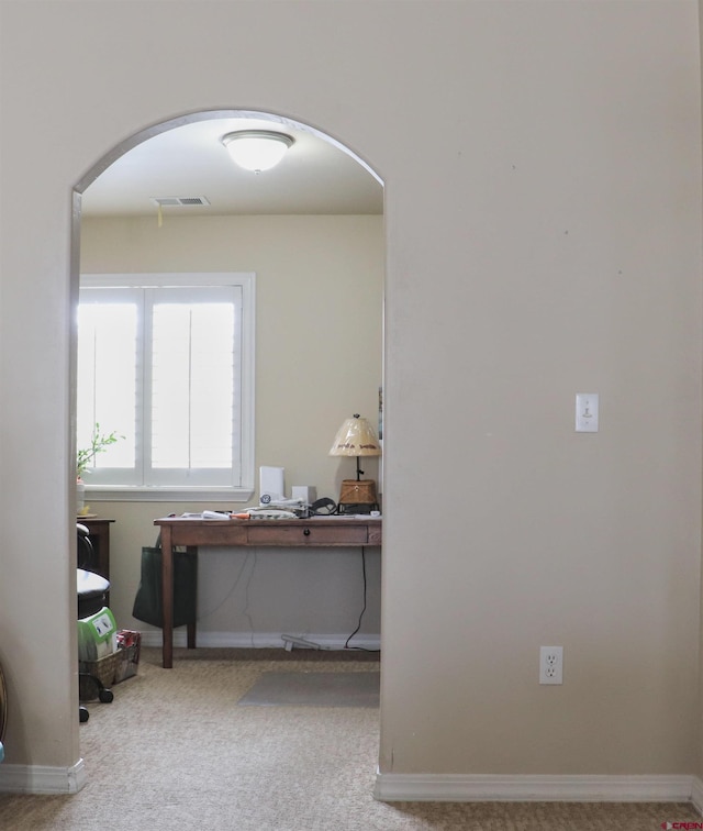 interior space featuring arched walkways, carpet flooring, visible vents, and baseboards