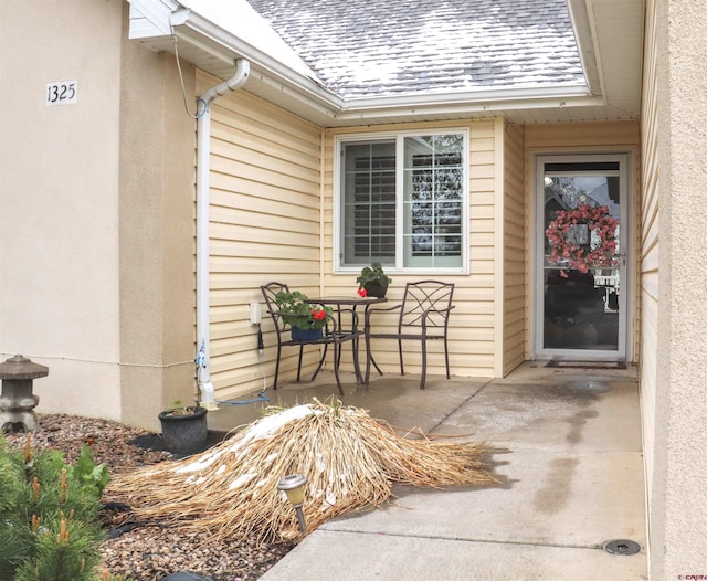 property entrance with stucco siding and a shingled roof