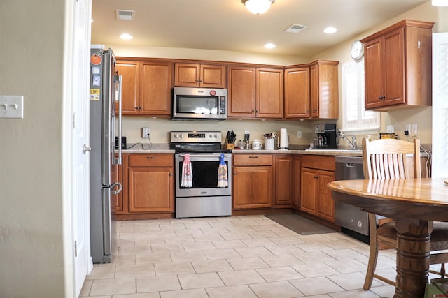 kitchen with brown cabinetry, appliances with stainless steel finishes, and light countertops