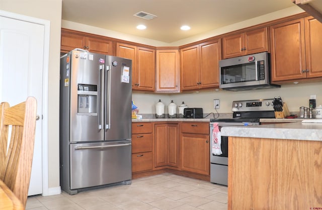 kitchen featuring brown cabinets, light tile patterned floors, light countertops, appliances with stainless steel finishes, and visible vents