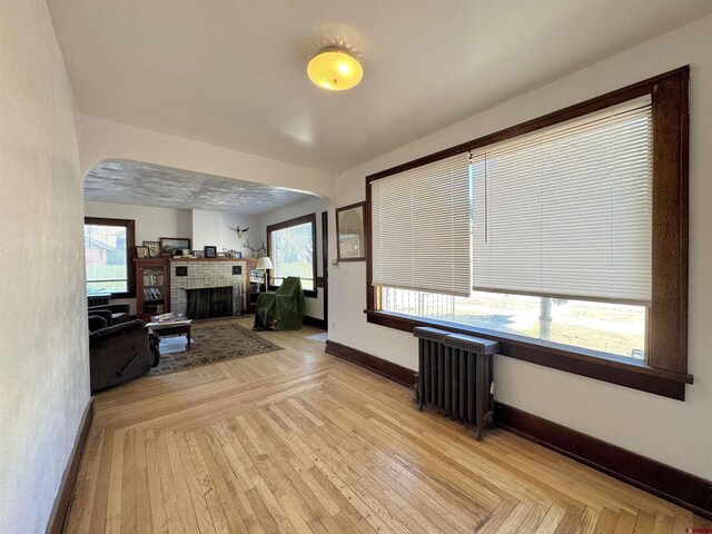 212 Bell Ave, Alamosa, CO 81101 - living area featuring baseboards, radiator, arched walkways, and a brick fireplace