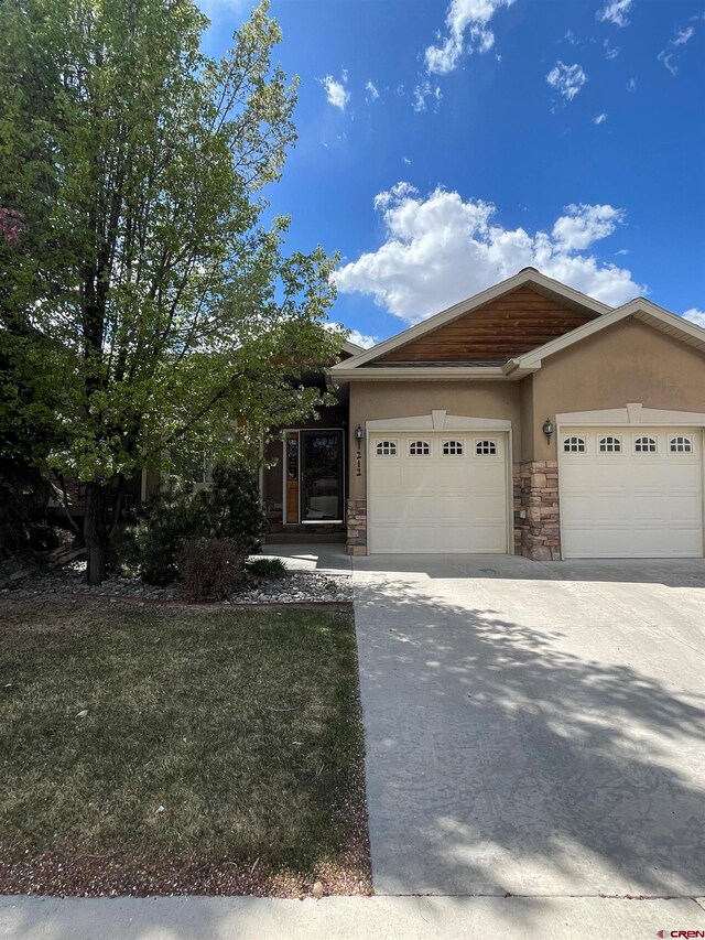 view of front of property with stucco siding, a garage, driveway, and stone siding