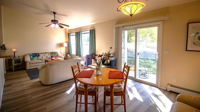 dining room with wood finished floors, ceiling fan, and baseboard heating