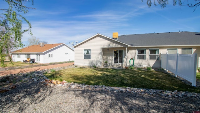 rear view of property with fence and a lawn