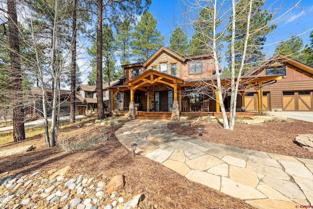 view of front facade featuring a porch, driveway, and stone siding