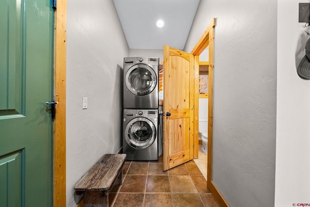 washroom featuring a textured wall, stacked washing maching and dryer, and laundry area