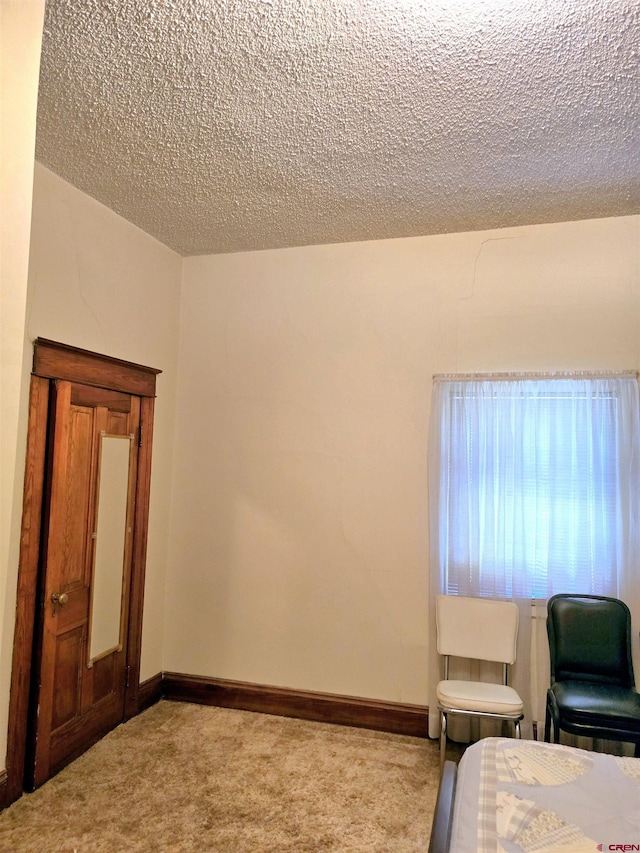 carpeted bedroom featuring a textured ceiling and baseboards