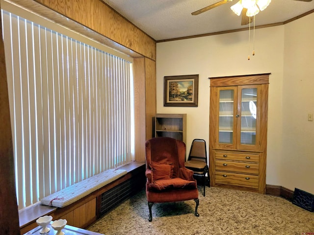 living area featuring carpet, ceiling fan, and ornamental molding