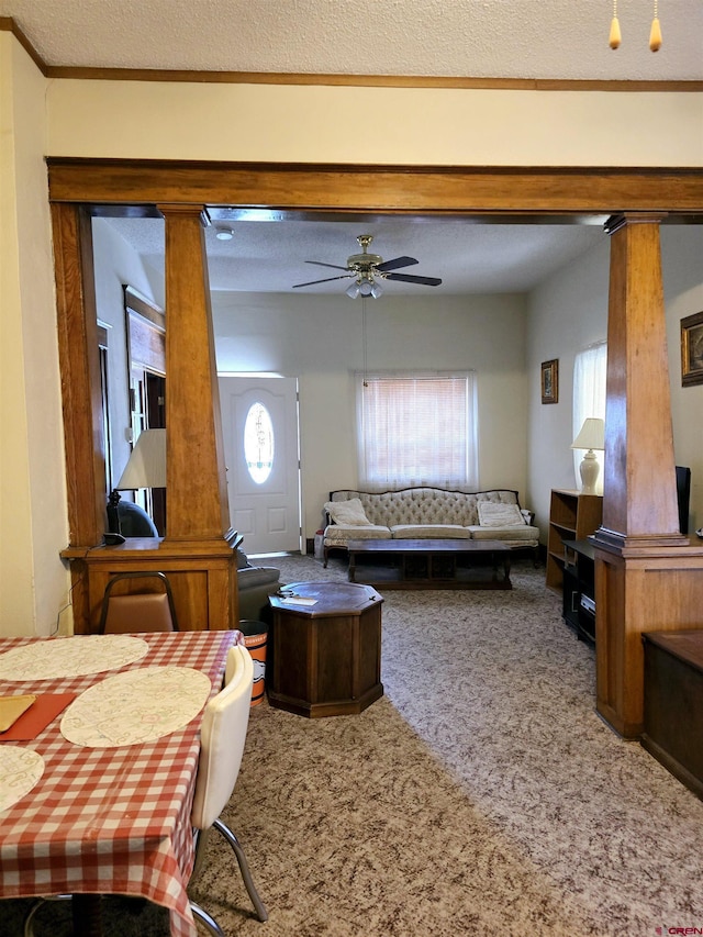 living area with ceiling fan, decorative columns, and carpet