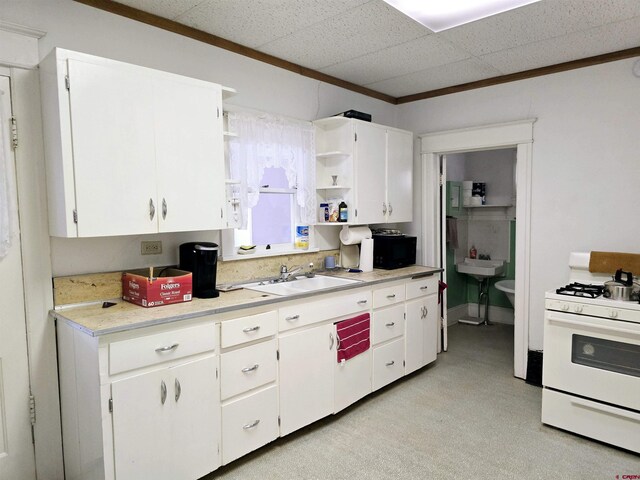 kitchen featuring white gas range, open shelves, white cabinets, and light countertops