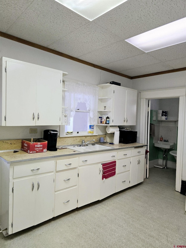 kitchen with a sink, open shelves, white cabinets, and light countertops