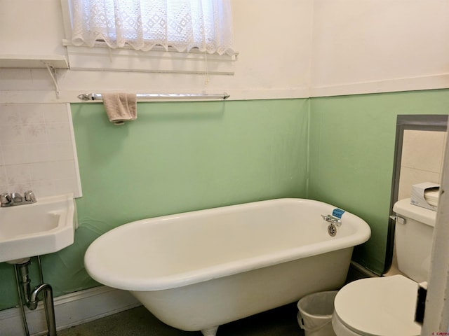 bathroom with toilet, a sink, and a freestanding bath