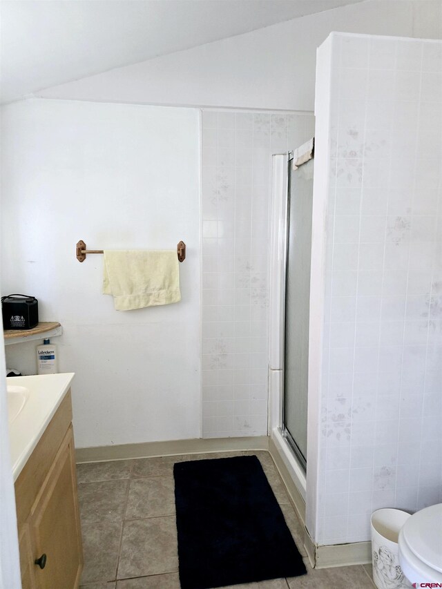full bathroom featuring lofted ceiling, a shower stall, toilet, tile patterned floors, and vanity