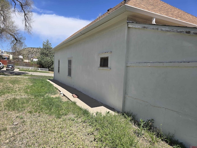 view of home's exterior with fence, stucco siding, and a lawn