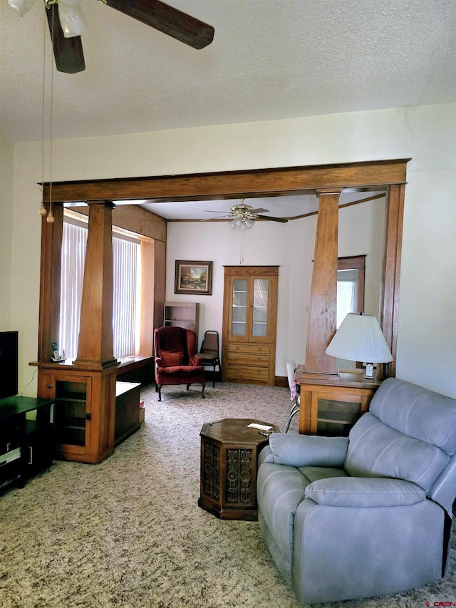 carpeted living area featuring a ceiling fan and a textured ceiling
