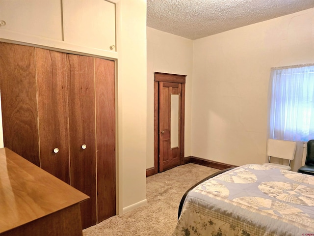 bedroom featuring a textured ceiling, a closet, carpet floors, and baseboards