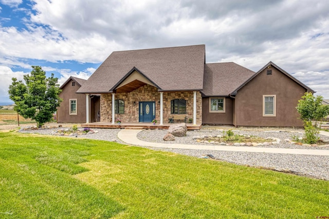 view of front of property with a porch, roof with shingles, a front lawn, stone siding, and stucco siding