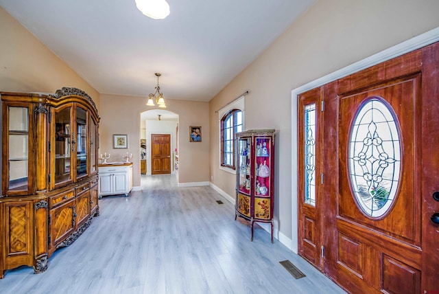 entryway with visible vents, arched walkways, light wood-style floors, and baseboards