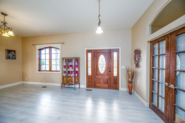 foyer with french doors, light wood finished floors, and baseboards