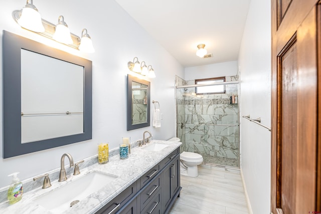 bathroom with a sink, a shower stall, toilet, and double vanity