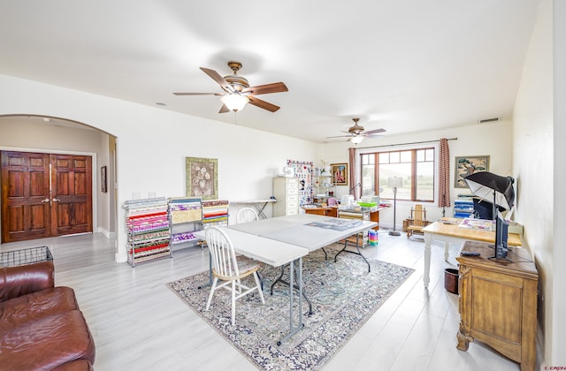 dining area with arched walkways, ceiling fan, visible vents, and wood finished floors