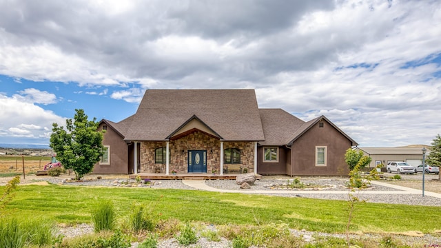 view of front of house with covered porch, stone siding, and a front lawn