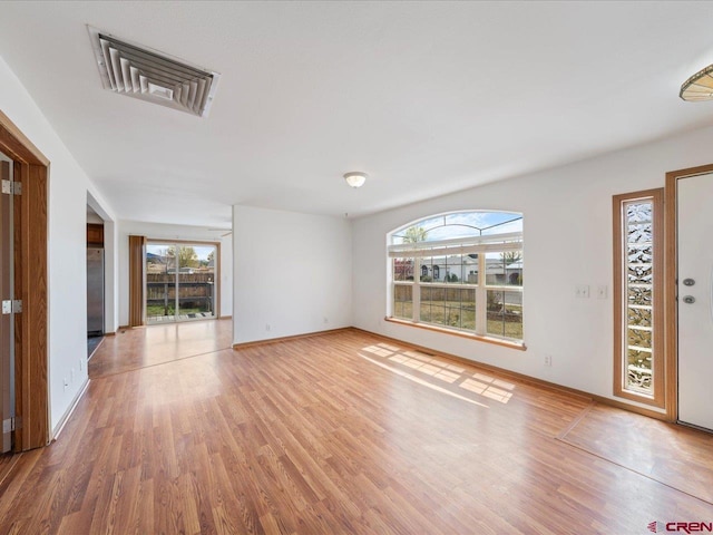 unfurnished living room with visible vents, wood finished floors, and a wealth of natural light