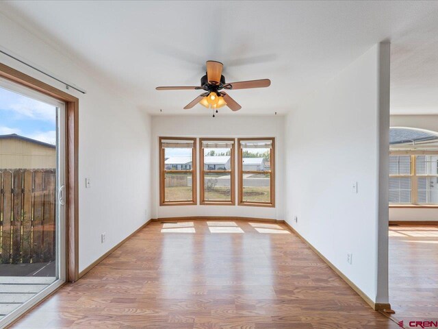 unfurnished room with baseboards, a ceiling fan, and wood finished floors