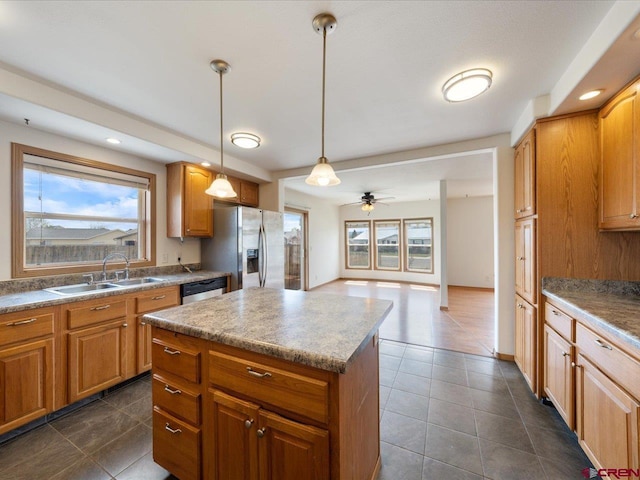 kitchen with dark tile patterned floors, a sink, appliances with stainless steel finishes, and a wealth of natural light