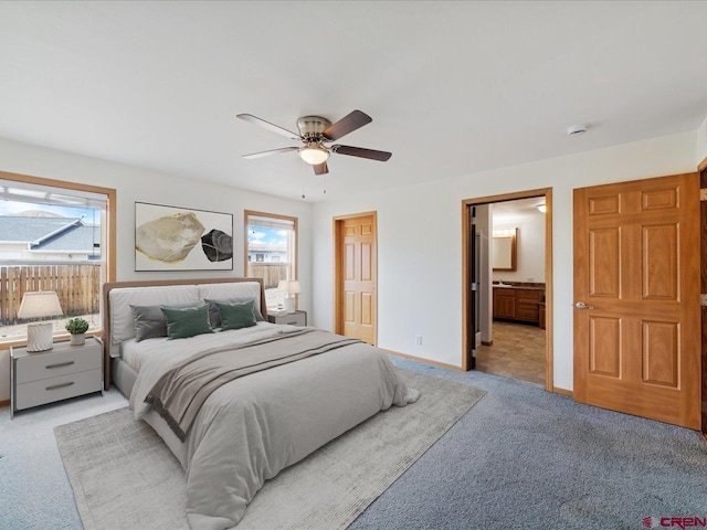 bedroom with light colored carpet, a ceiling fan, connected bathroom, and multiple windows