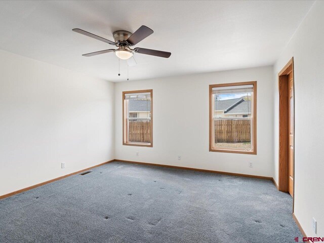 carpeted empty room with plenty of natural light, a ceiling fan, and baseboards