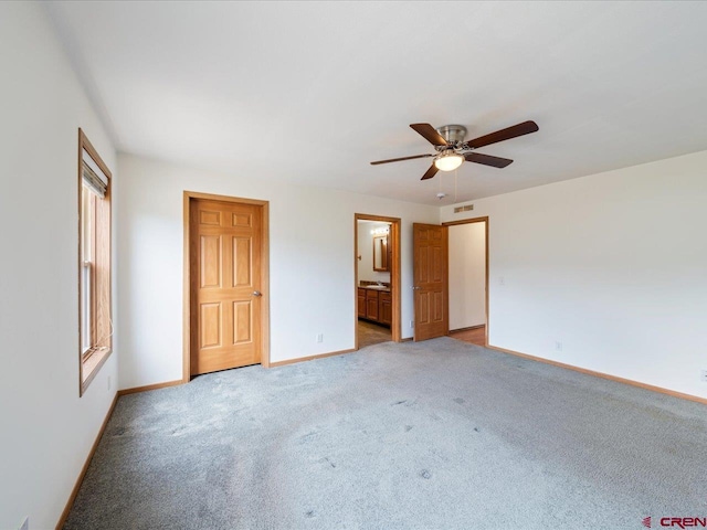 unfurnished bedroom featuring ceiling fan, visible vents, baseboards, connected bathroom, and light carpet