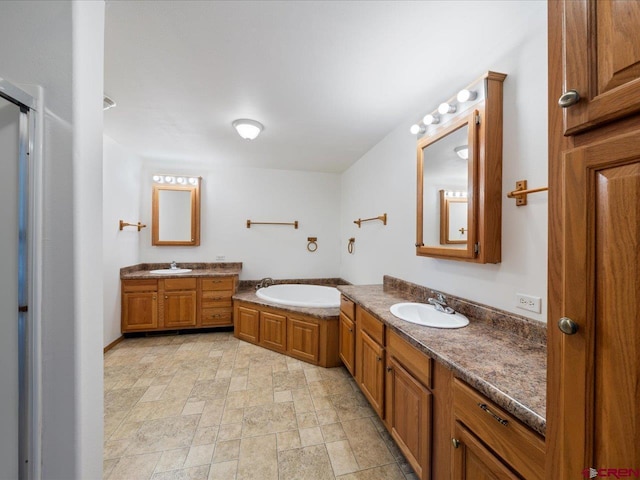 full bathroom with a sink, a bath, stone finish floor, and two vanities