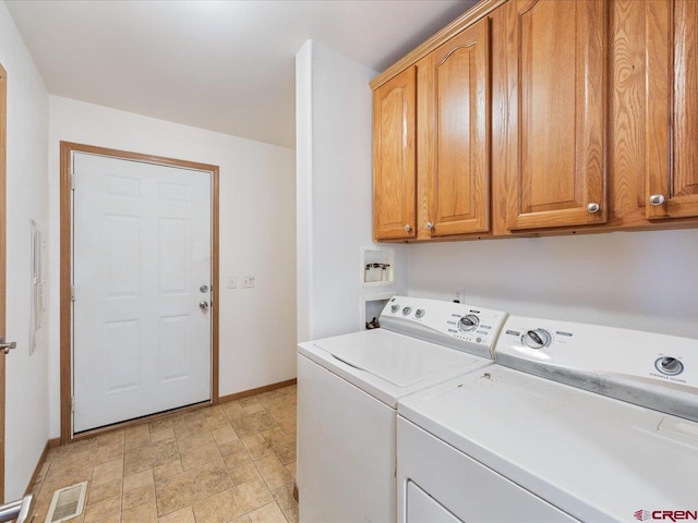 laundry area with cabinet space, stone finish floor, baseboards, visible vents, and washer and clothes dryer