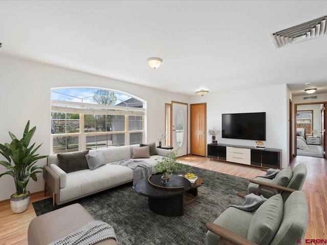 living area featuring visible vents and wood finished floors