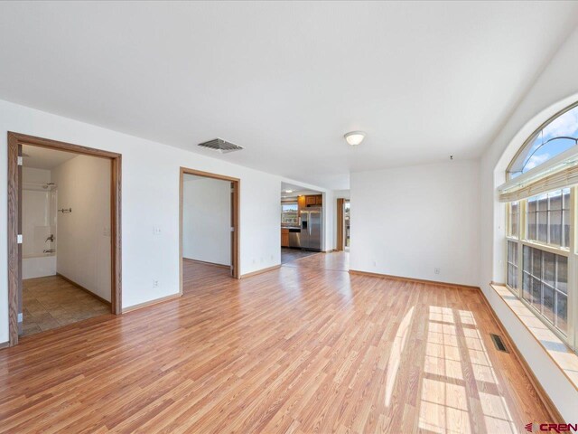 unfurnished living room with baseboards, light wood-style flooring, and visible vents