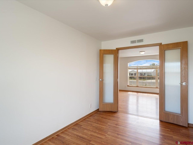 spare room with visible vents, baseboards, and wood finished floors