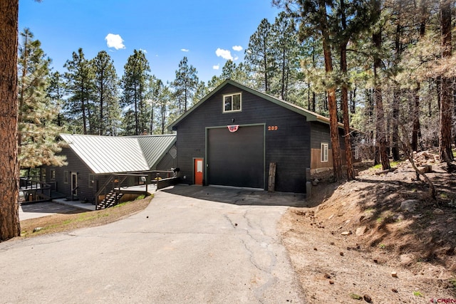 chalet / cabin with a garage, driveway, a standing seam roof, and metal roof